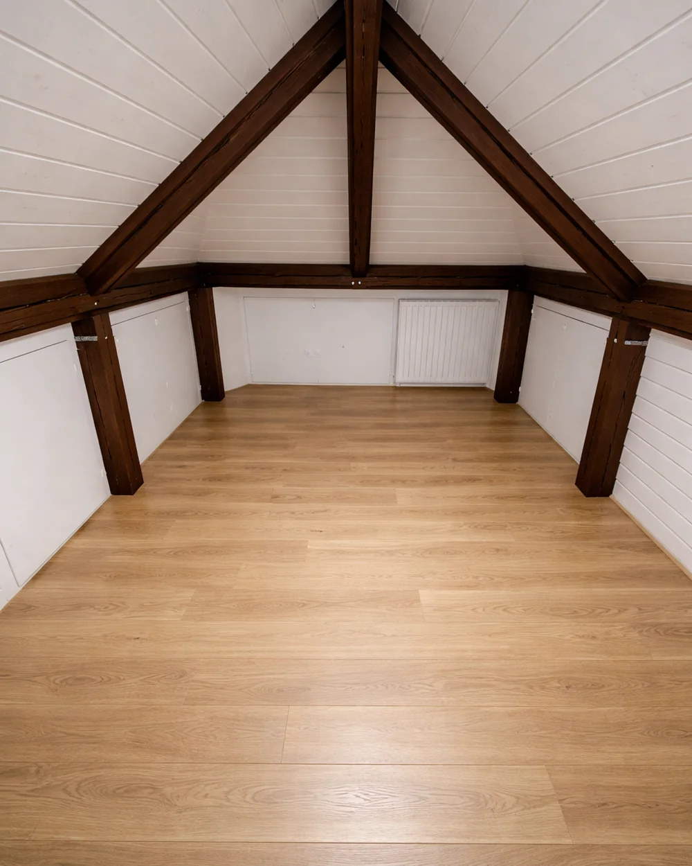 Comble aménagé par Renova Swiss, charpente apparente et parquet chêne